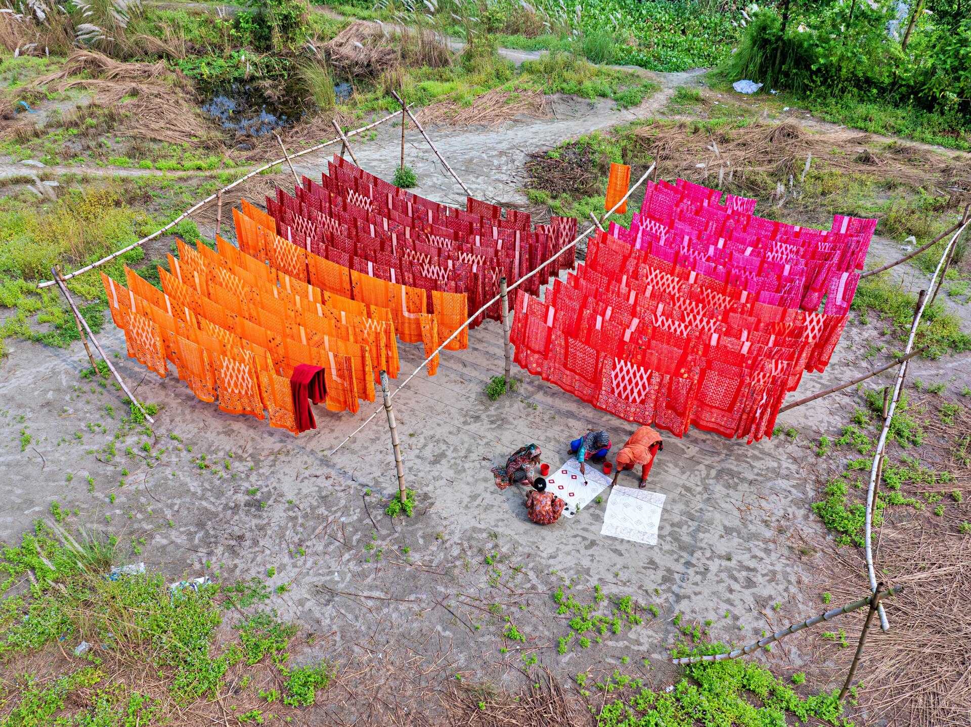 Long lengths of colorful fabric drying outdoors in sunlight