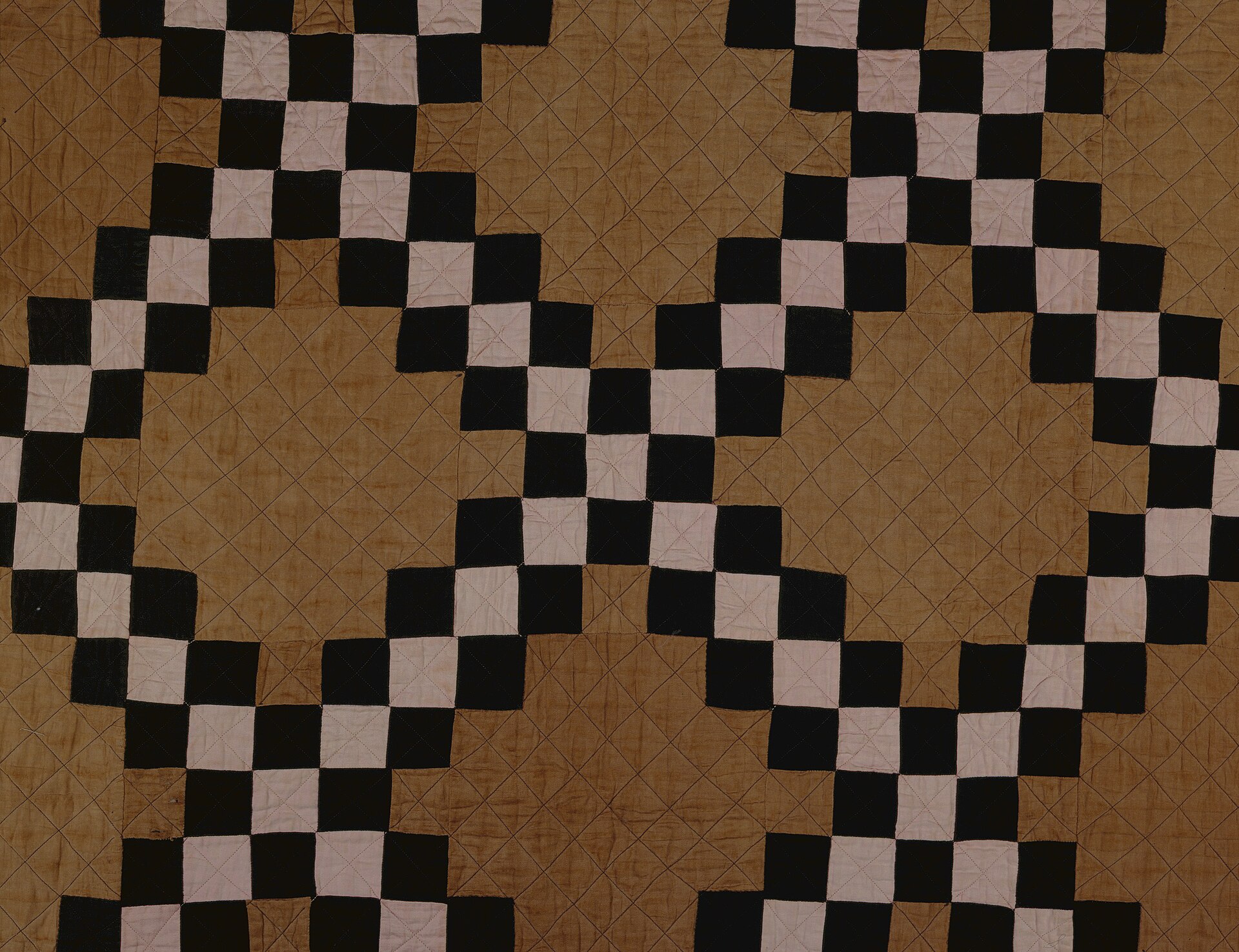 Pink, black, and brown patchwork quilt in a chain pattern